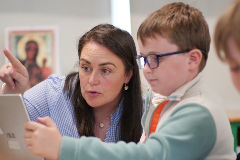 Teacher and child looking at a laptop screen together